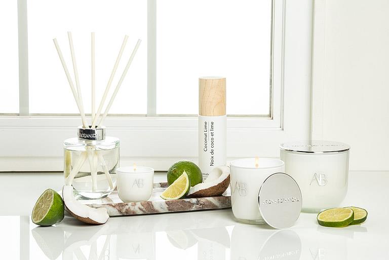 Candles and diffusers with lime slices on a white surface near a window