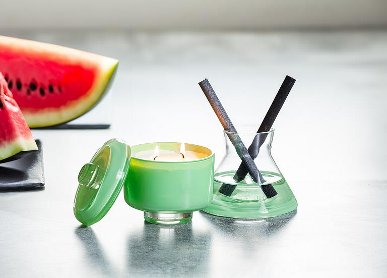 Green candle with a watermelon slice on a reflective surface