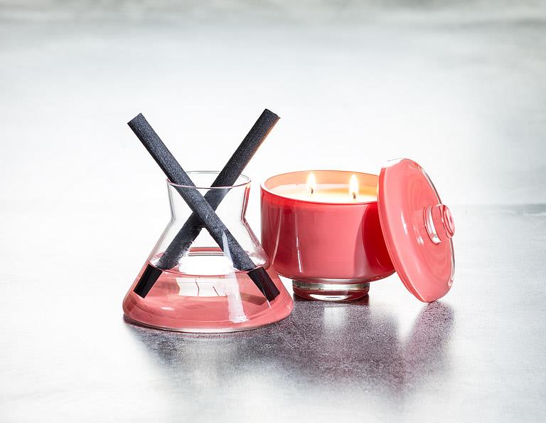 Red candle with a pink lid and black wick on a white background