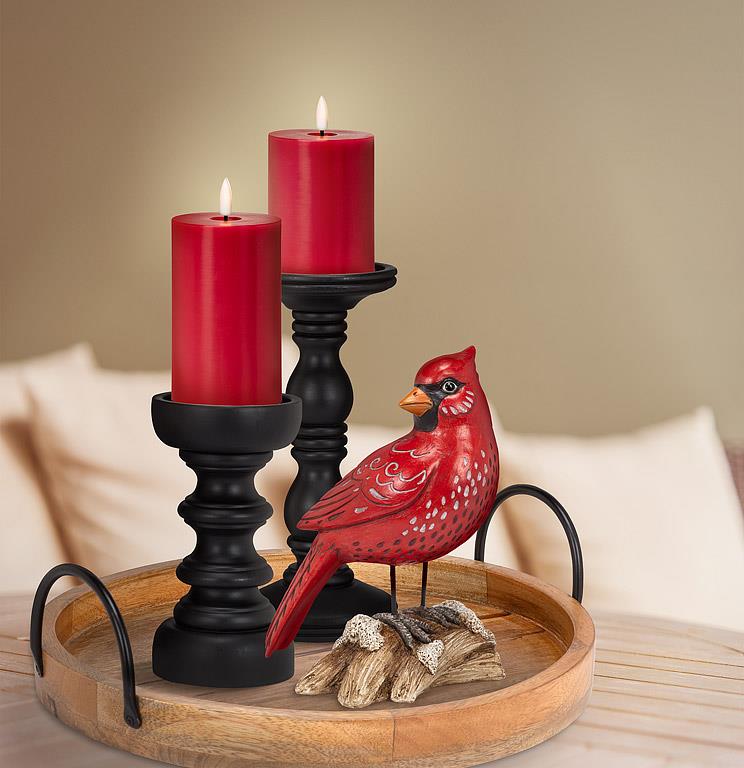 Red candles in black candlesticks with a red cardinal bird figurine on a wooden tray.
