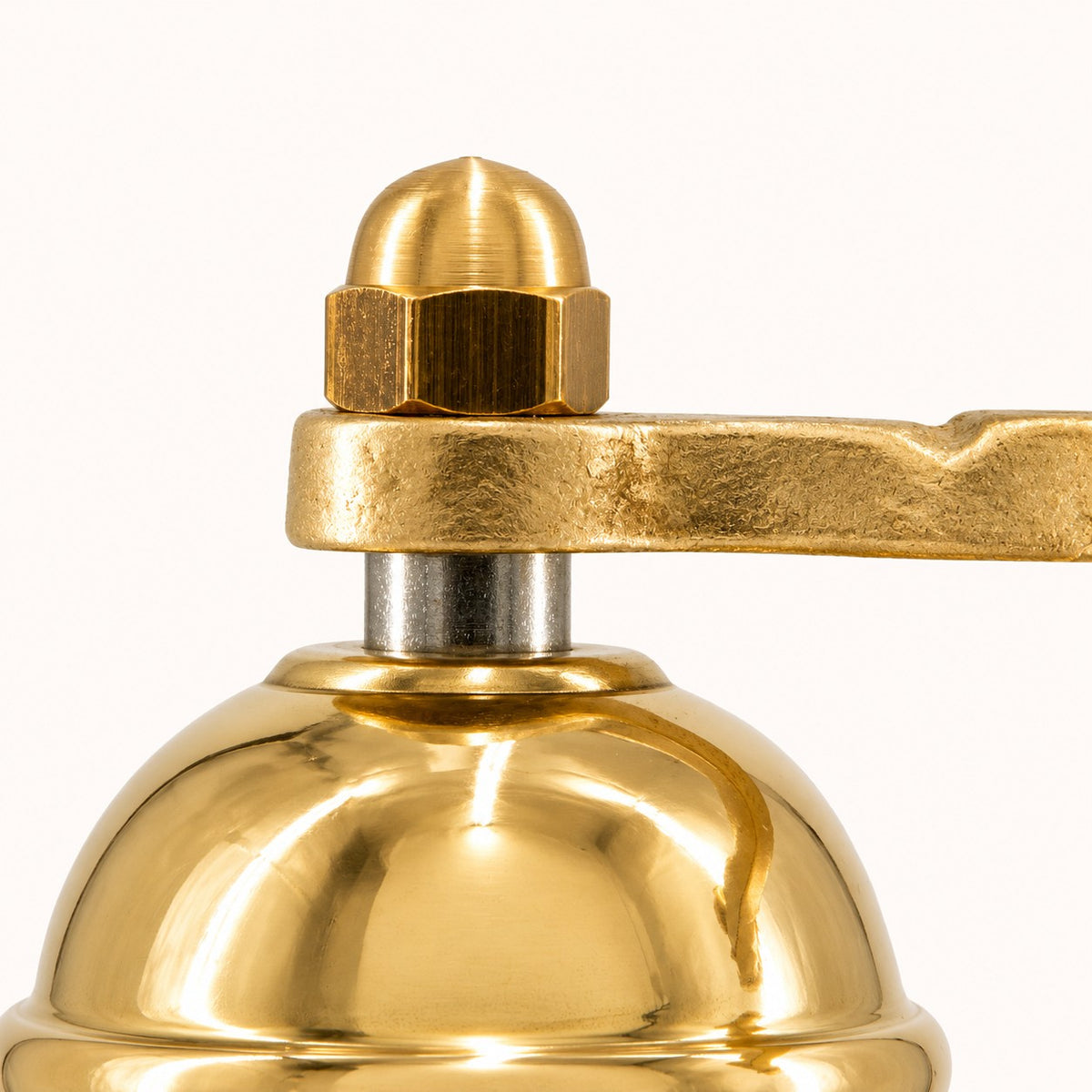 Close-up of a polished alexander brass mill with a matching brass handle and nut on a white background.