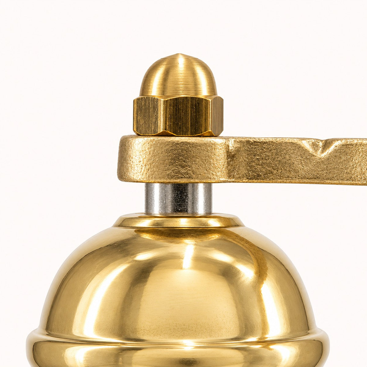 Close-up of a polished brass bell with a matching brass handle and nut, set against a plain white background.