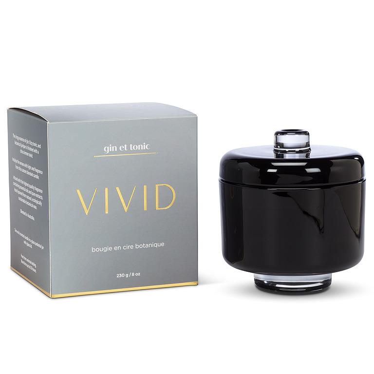 Black candle with a lid next to its packaging on a white background