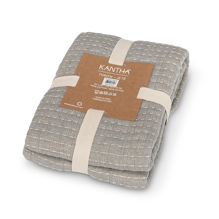 Folded gray KANtha throw blanket with a brown label on a white background