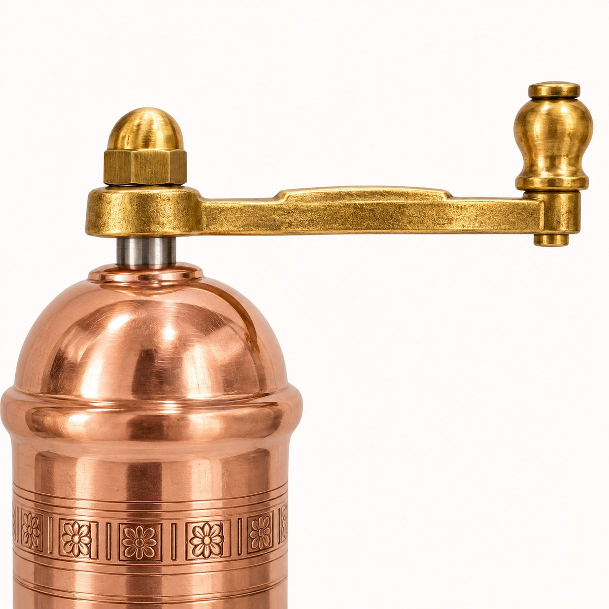 A close-up of a copper and brass hand-crank grinder against a solid white background.